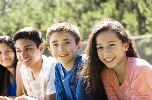 Group of smiling children outdoors, looking at the camera.