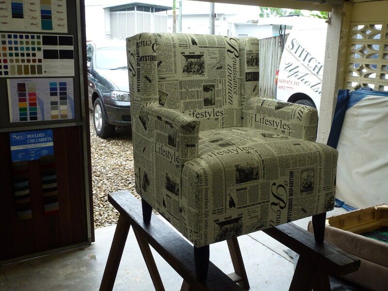 A Chair With A Newspaper Pattern Is Sitting On A Wooden Stand — Stitch Master in Manunda, QLD