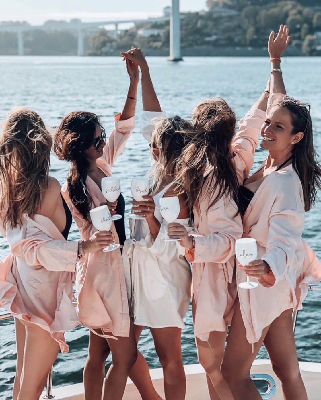 A group of women are standing on a boat holding wine glasses.