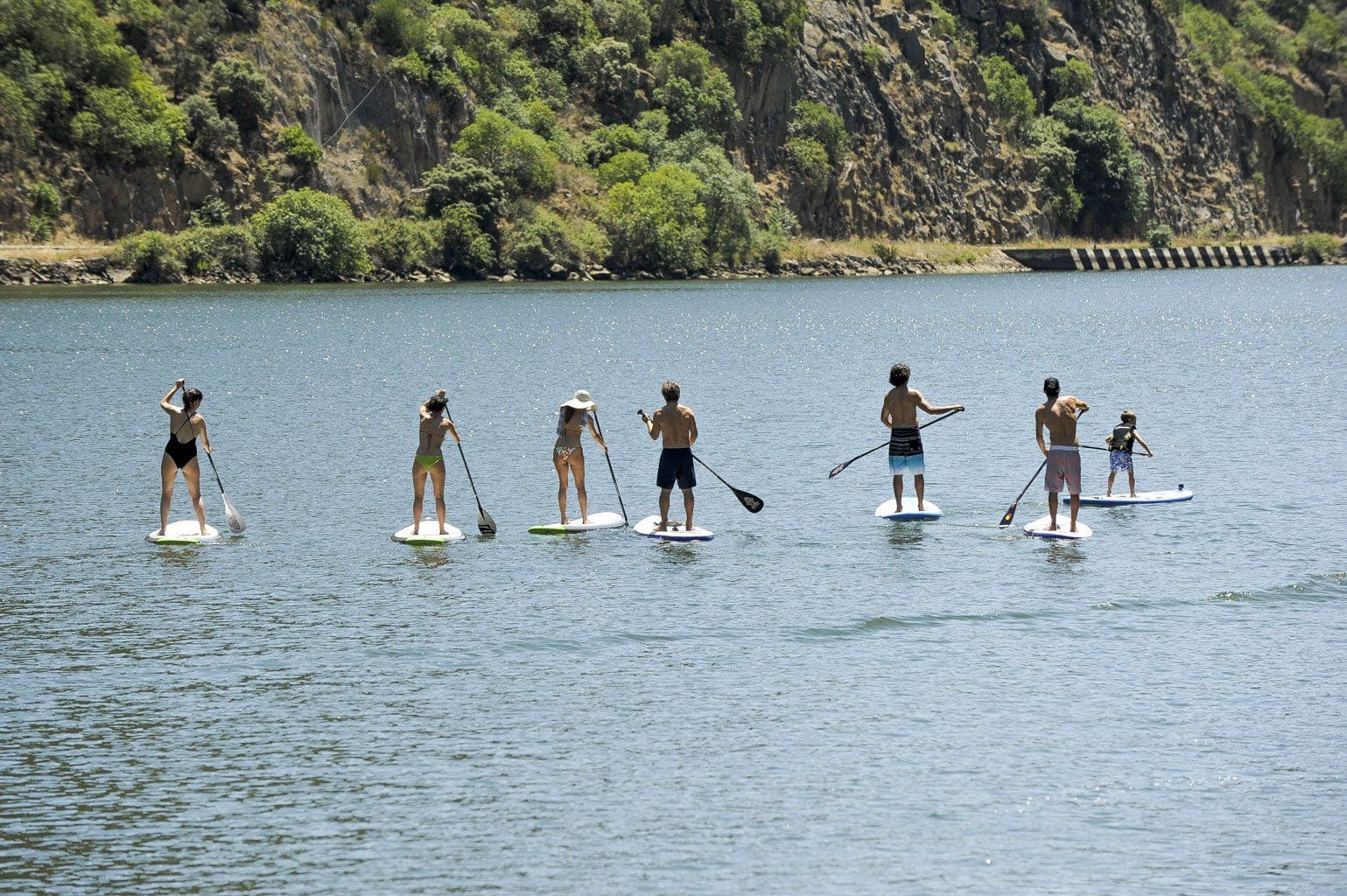 A group of people are riding paddle boards on a lake.
