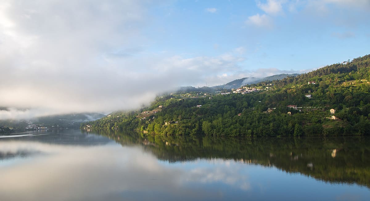 Um lago cercado por montanhas e árvores em um dia nublado