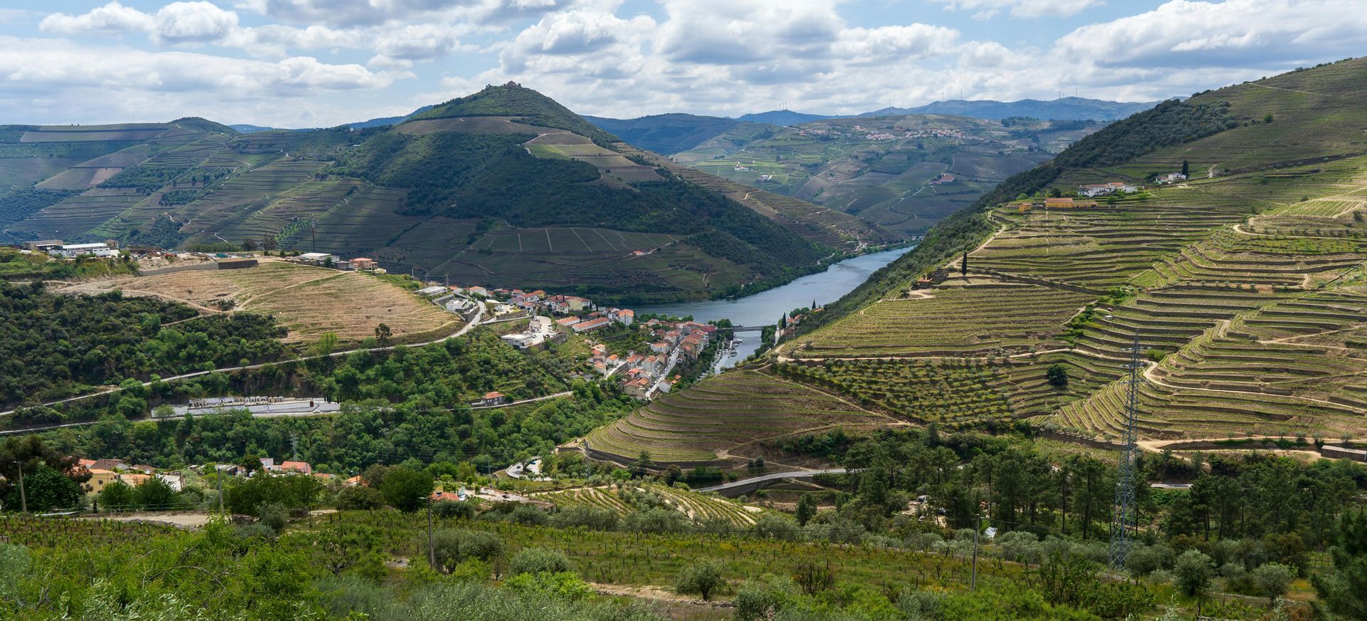 A river runs through a valley surrounded by mountains and trees.