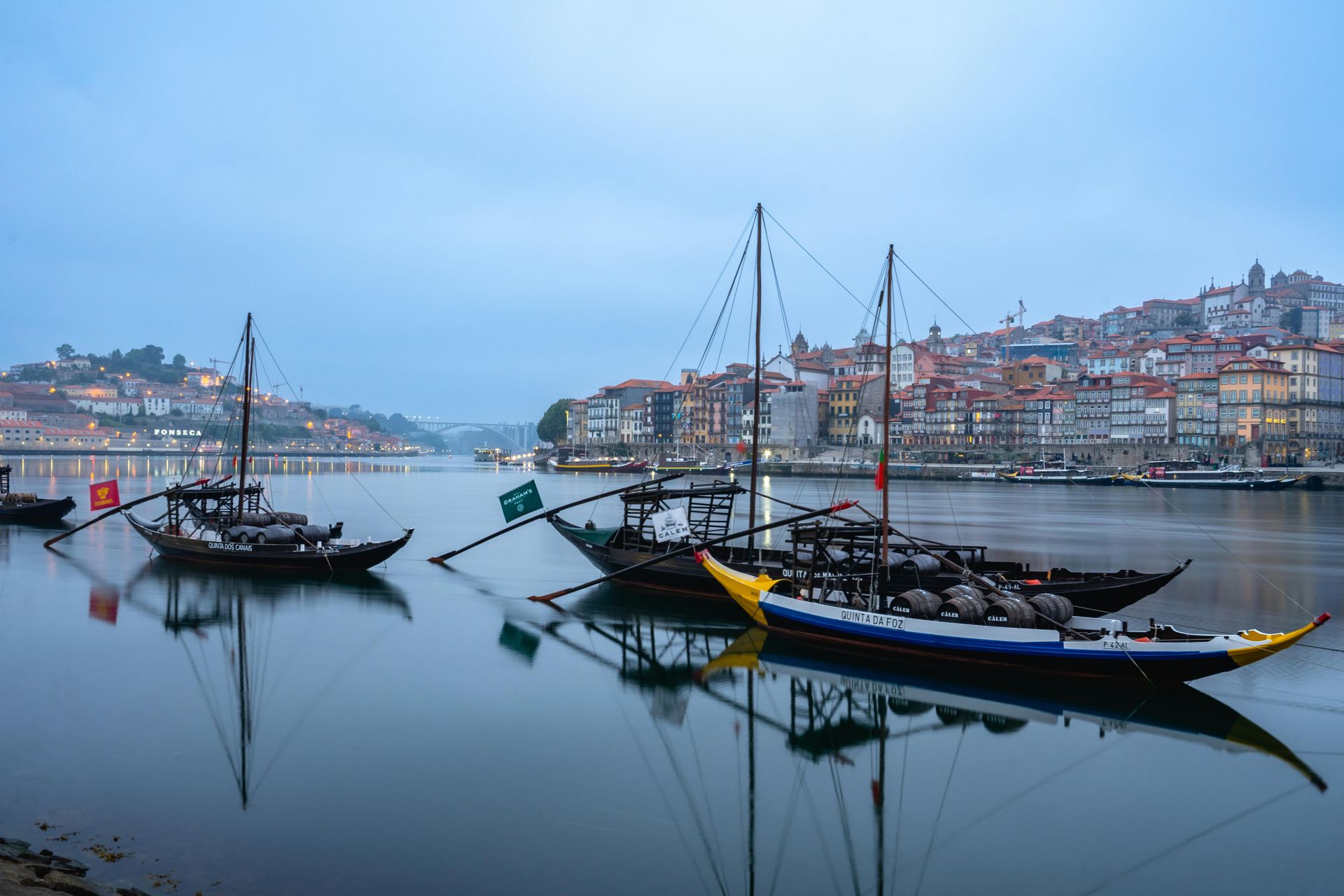A group of boats are docked in a harbor with a city in the background.