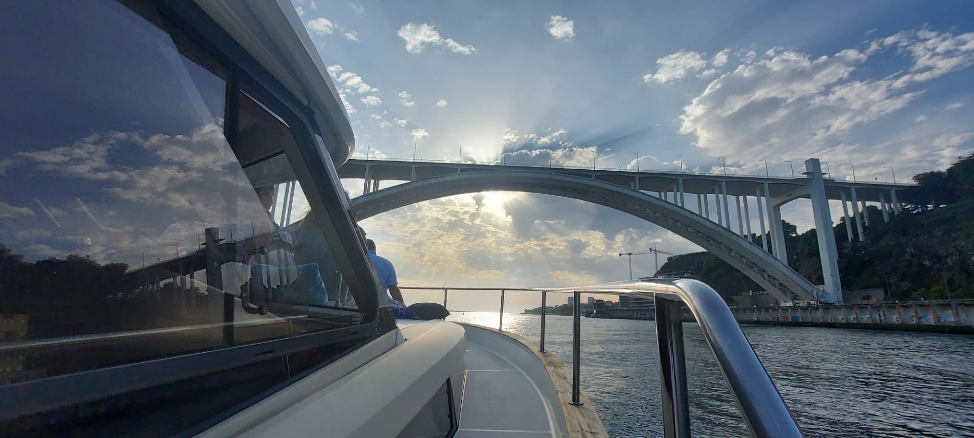 A boat is going under a bridge over a body of water.