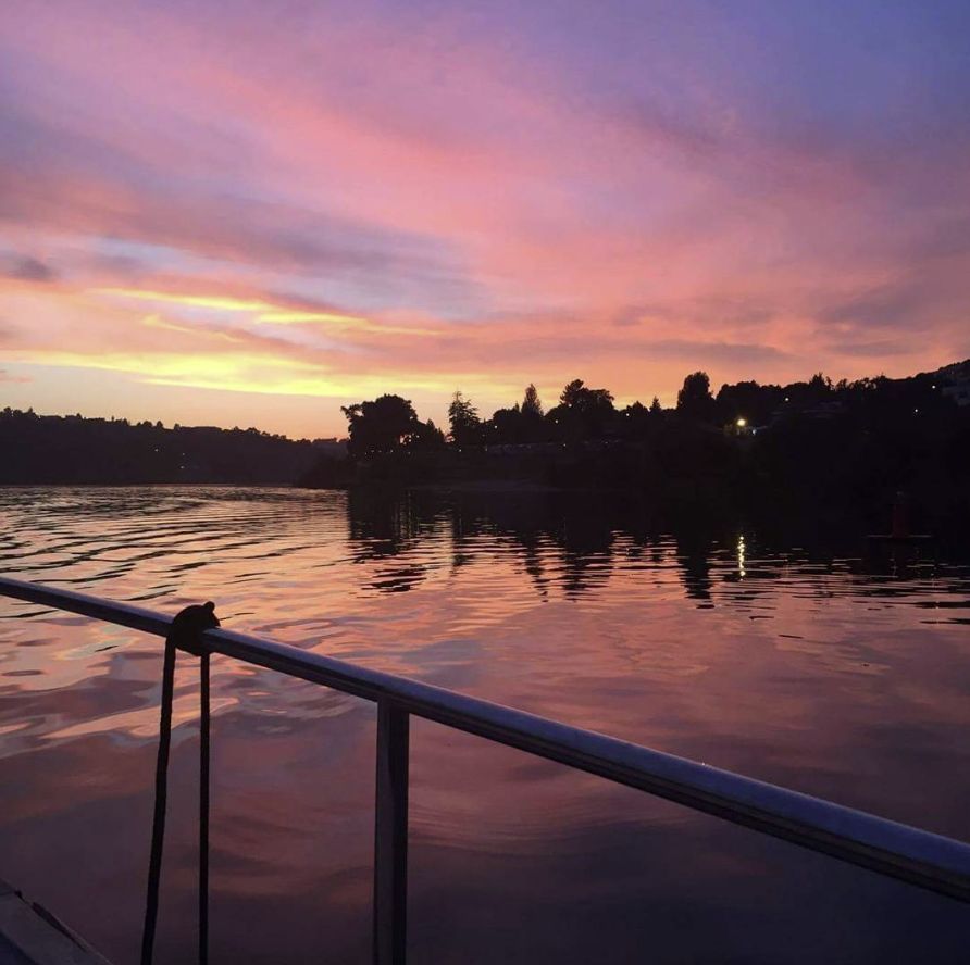A sunset over a body of water with a railing in the foreground
