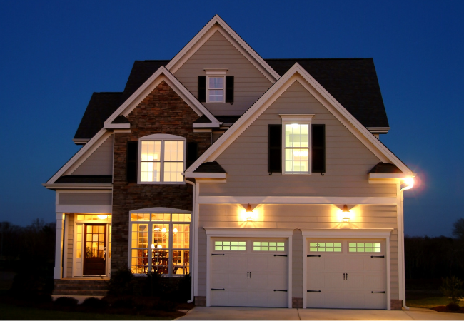 A house with two garage doors is lit up at night