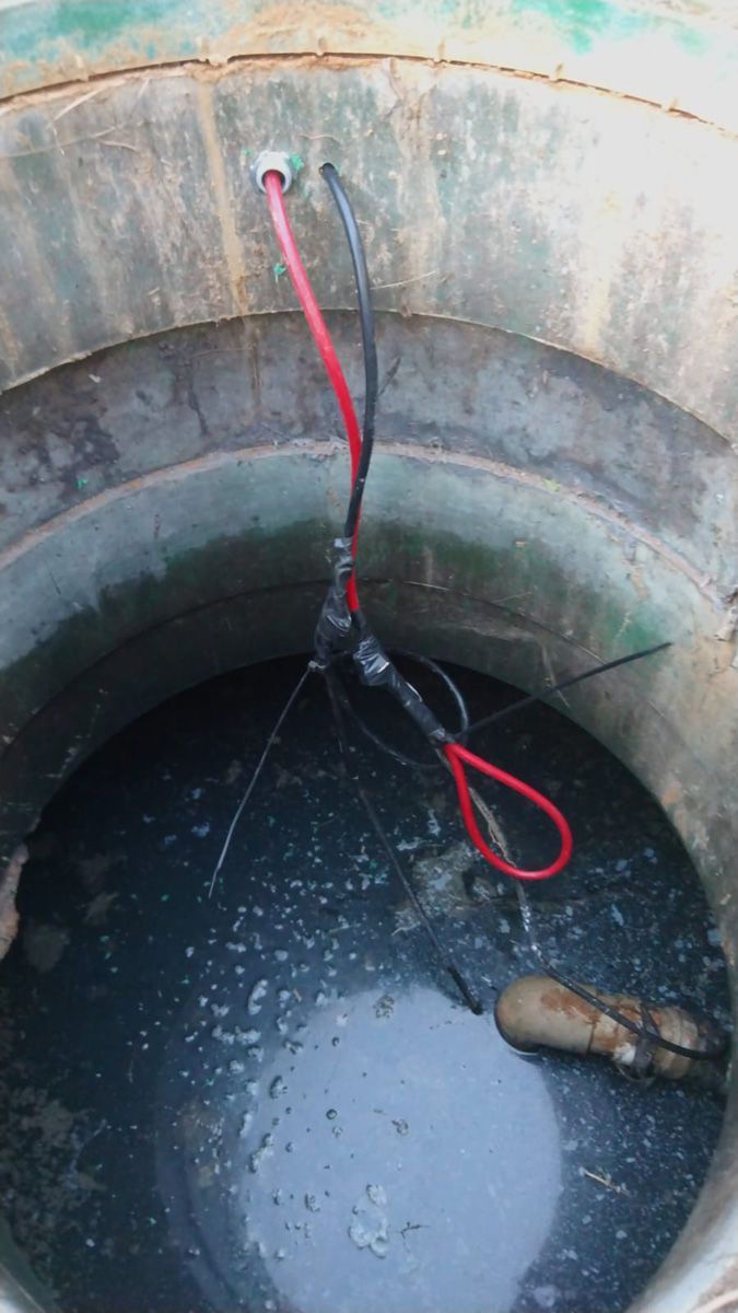 A well filled with water and a red and black hose.