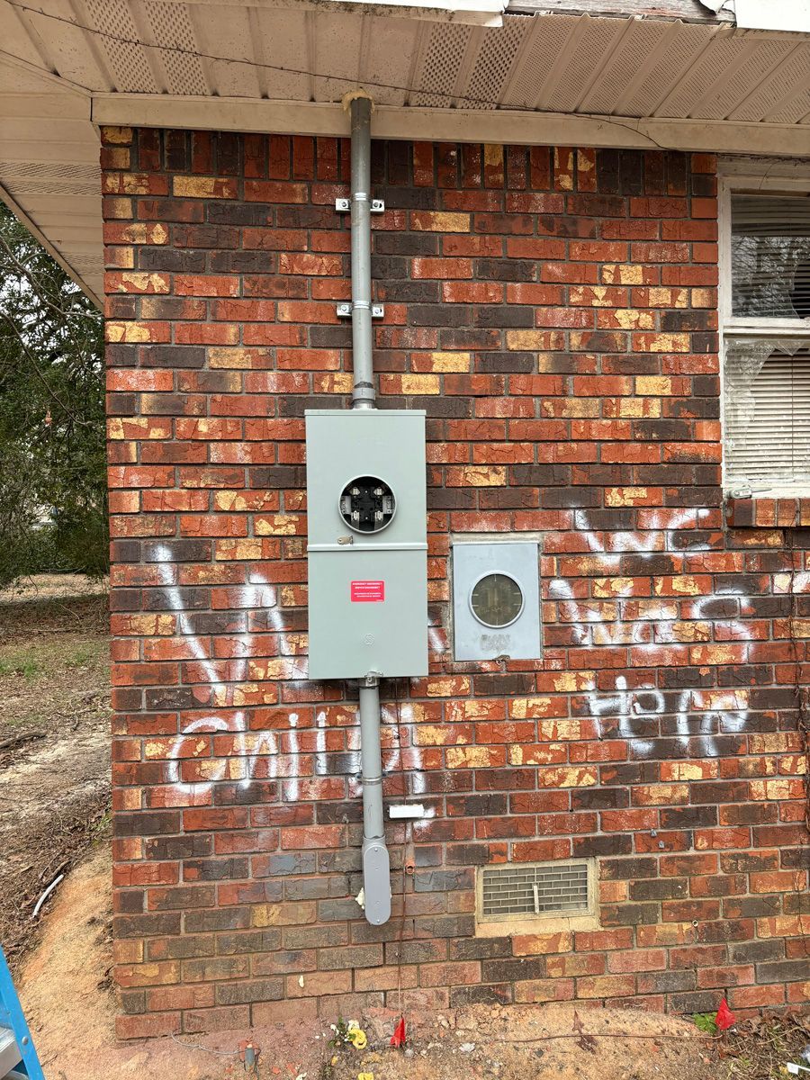 A brick wall with graffiti on it and a box on it.