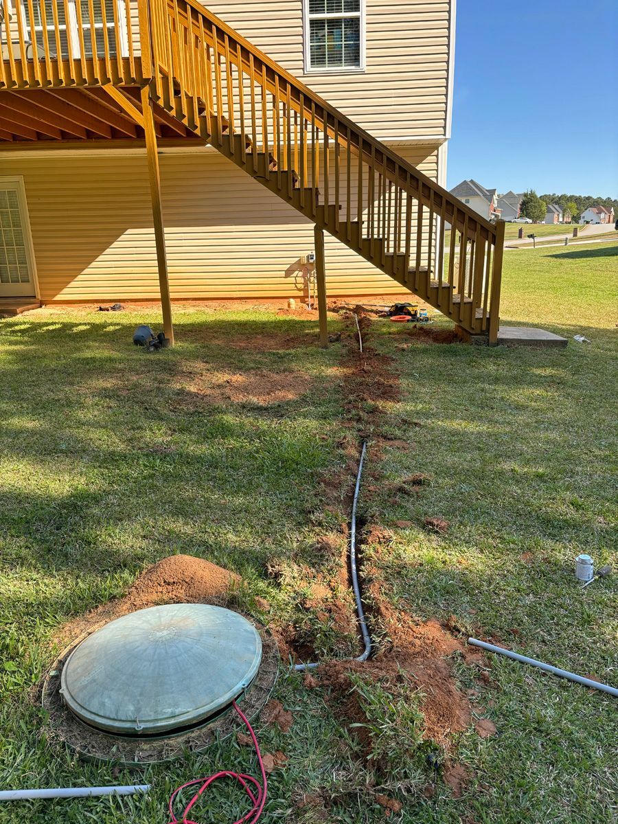A house with stairs and a septic tank in the backyard.