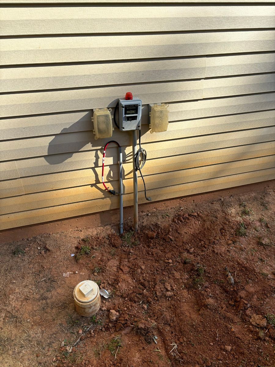 A water meter is sitting on the side of a house.