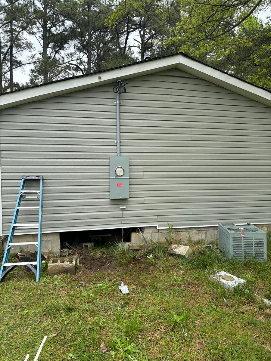 A mobile home with a ladder in the grass in front of it.