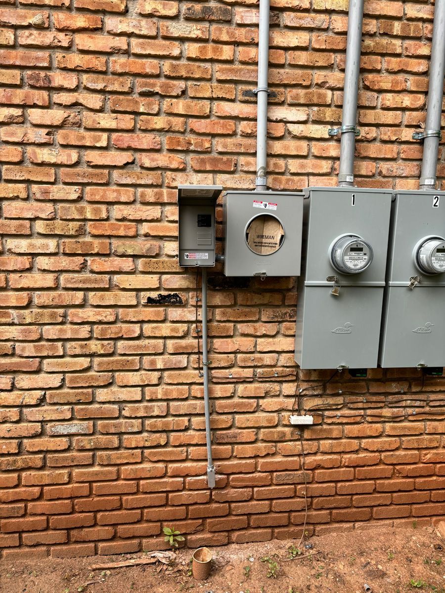 A brick wall with a bunch of electrical boxes on it