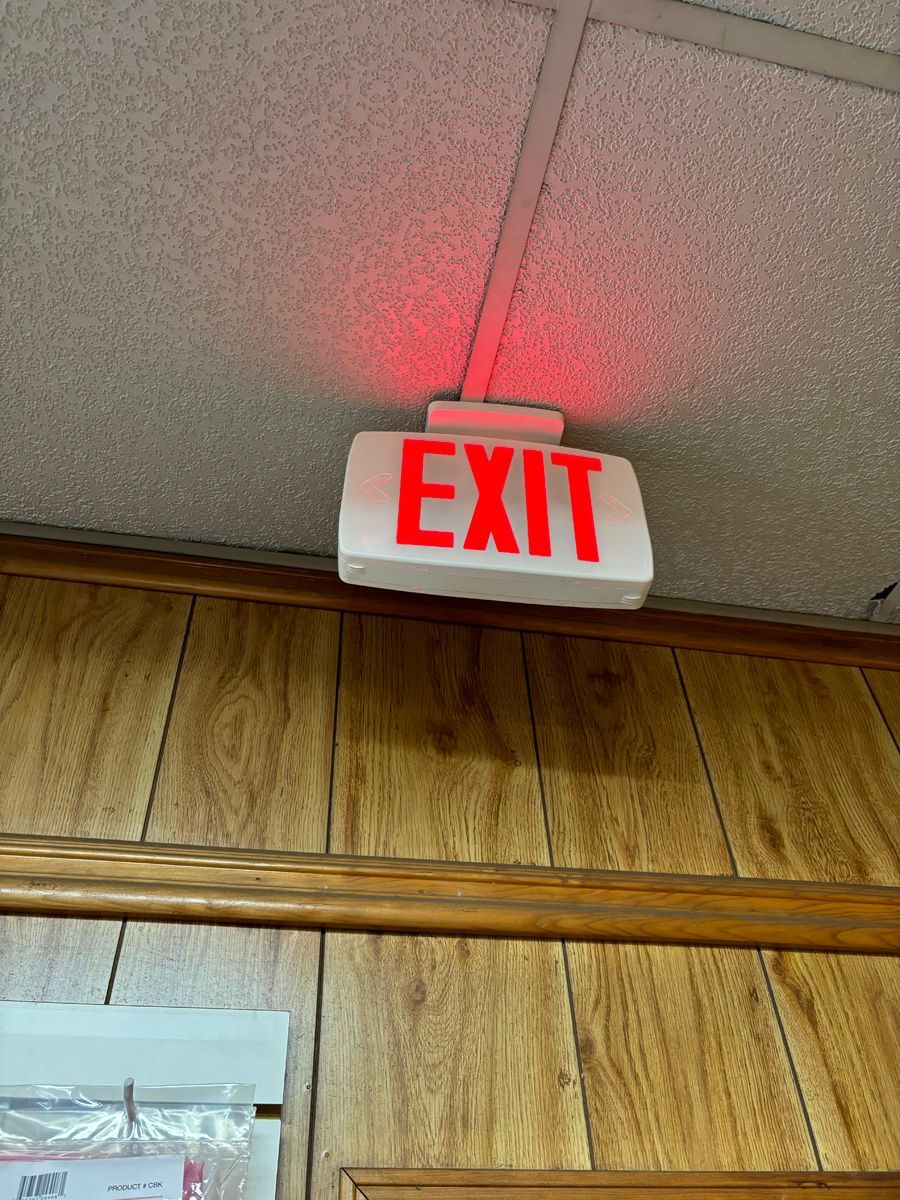 A red exit sign is lit up on a wooden wall