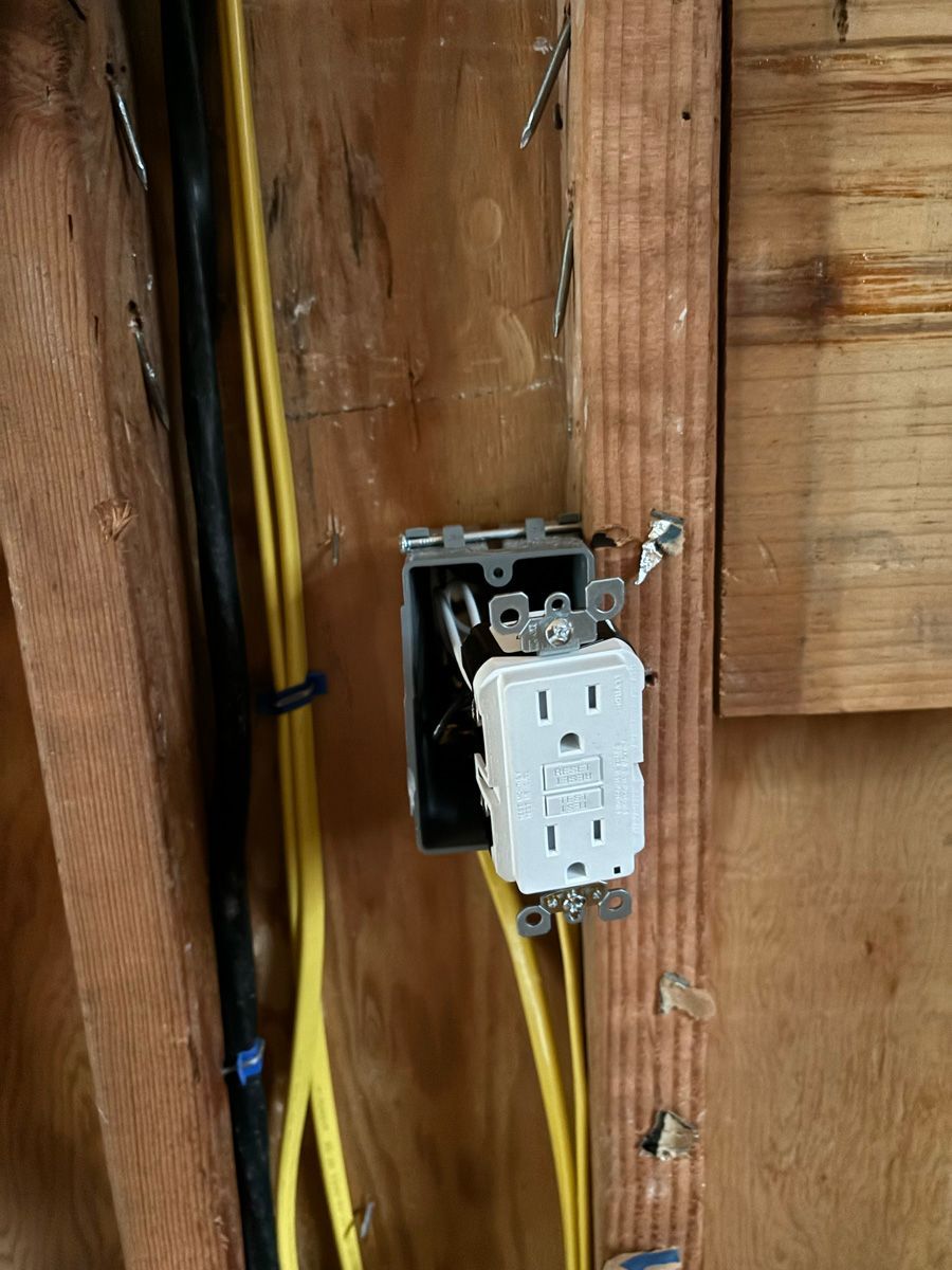 A close up of a electrical outlet on a wooden wall.
