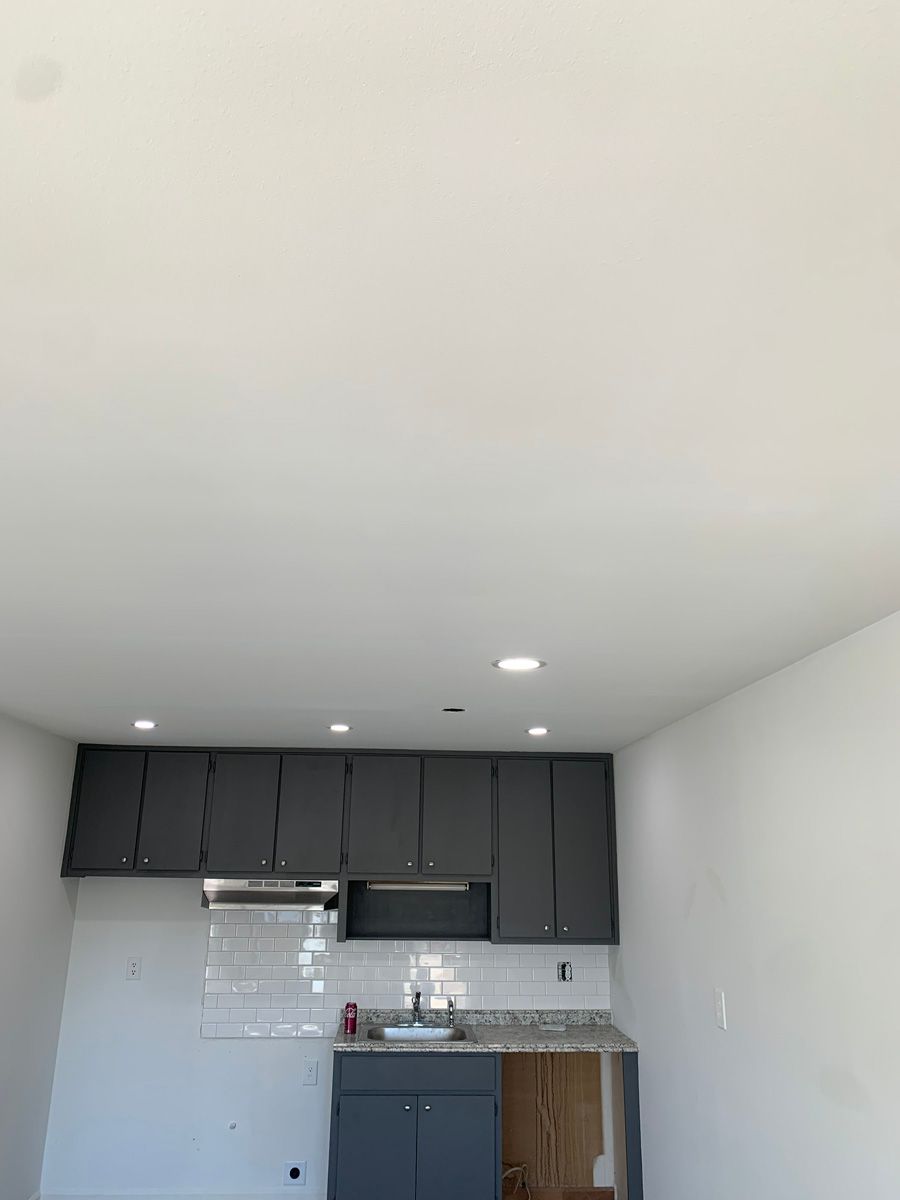 A kitchen with gray cabinets and a white ceiling.