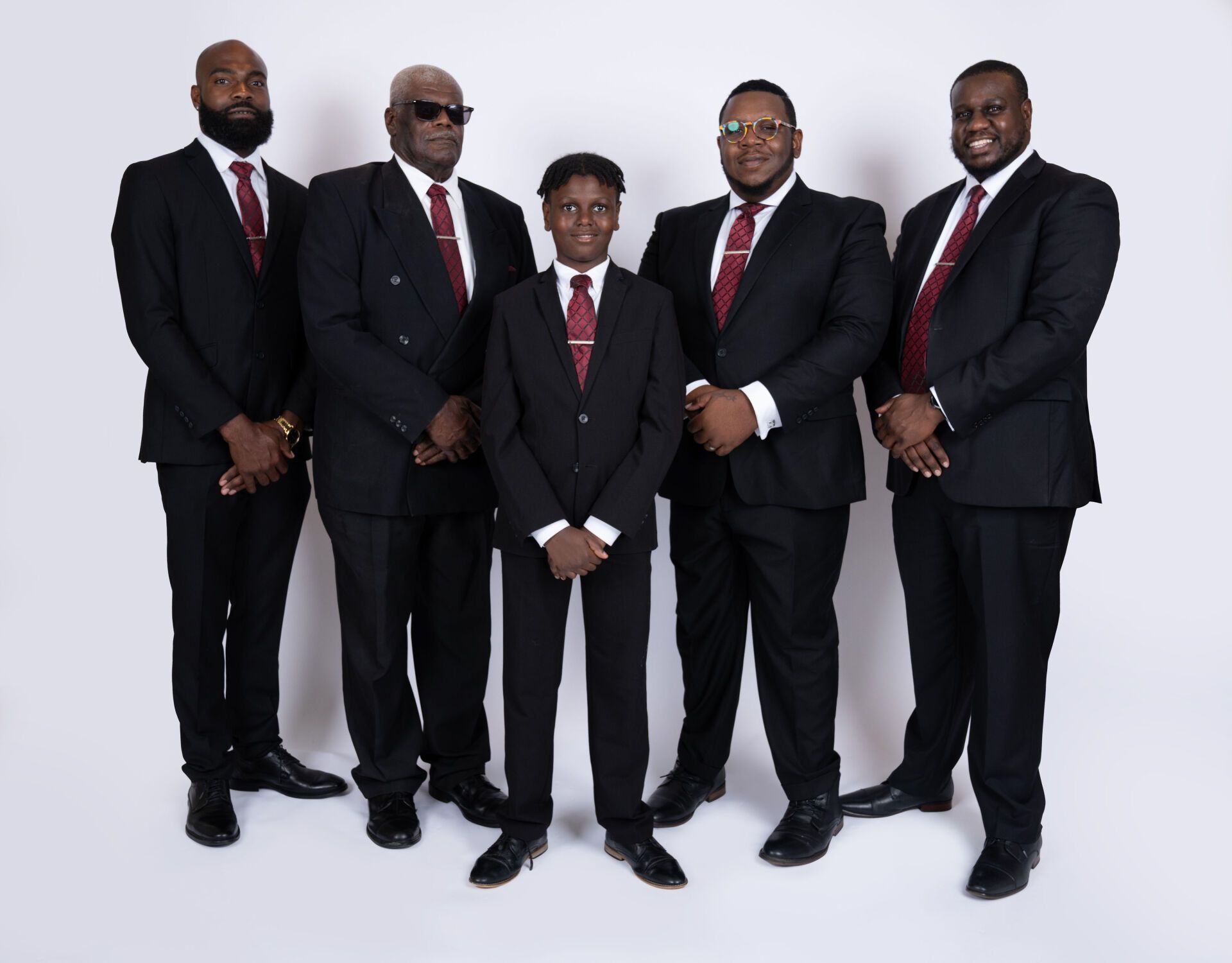 Five people in black suits and burgundy ties pose against a white background.