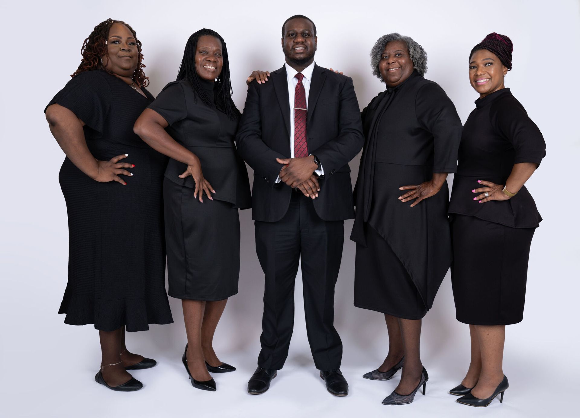 Five people in professional attire posing for a photo. One man in a suit, four women in black dresses.