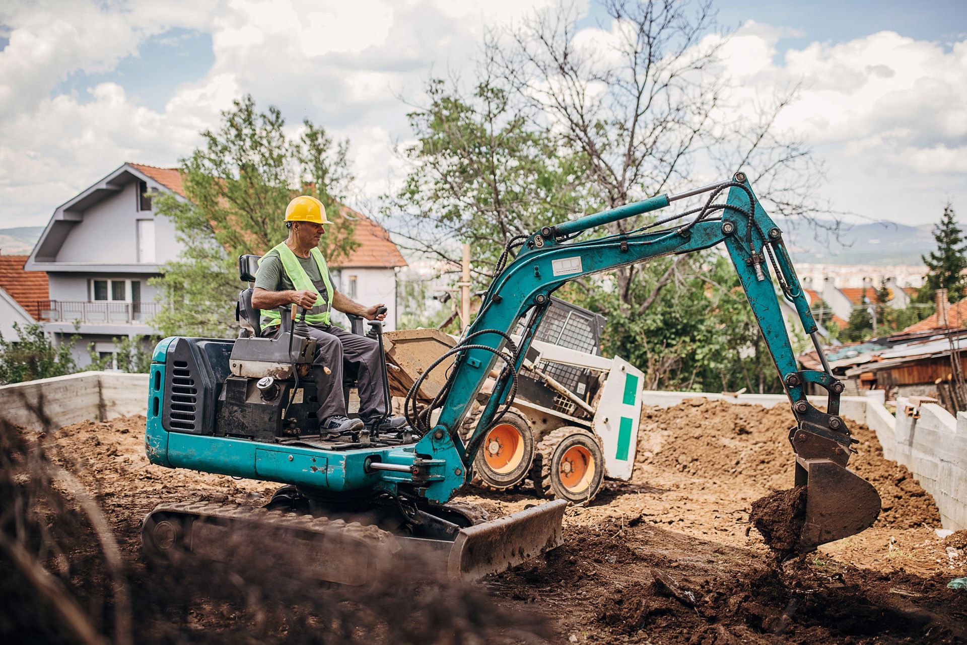 A man is driving a small excavator on a construction site.