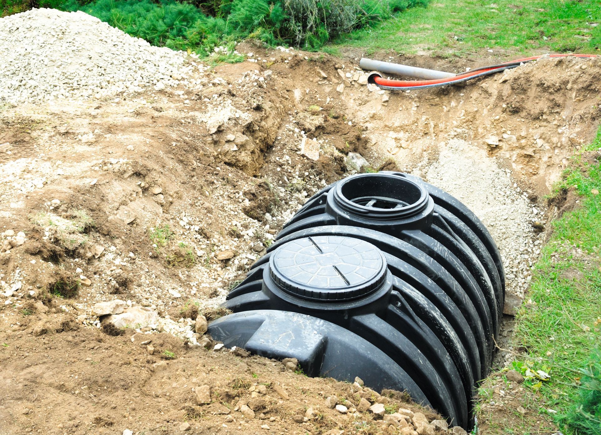 A large black septic tank is sitting in the middle of a dirt field.
