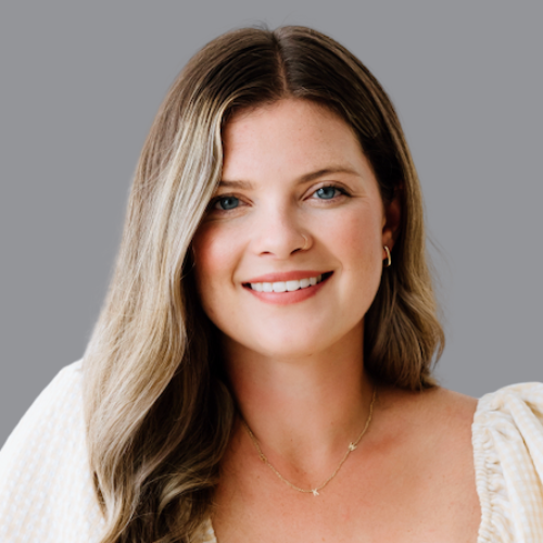 A woman wearing a white shirt and a gold necklace is smiling for the camera.