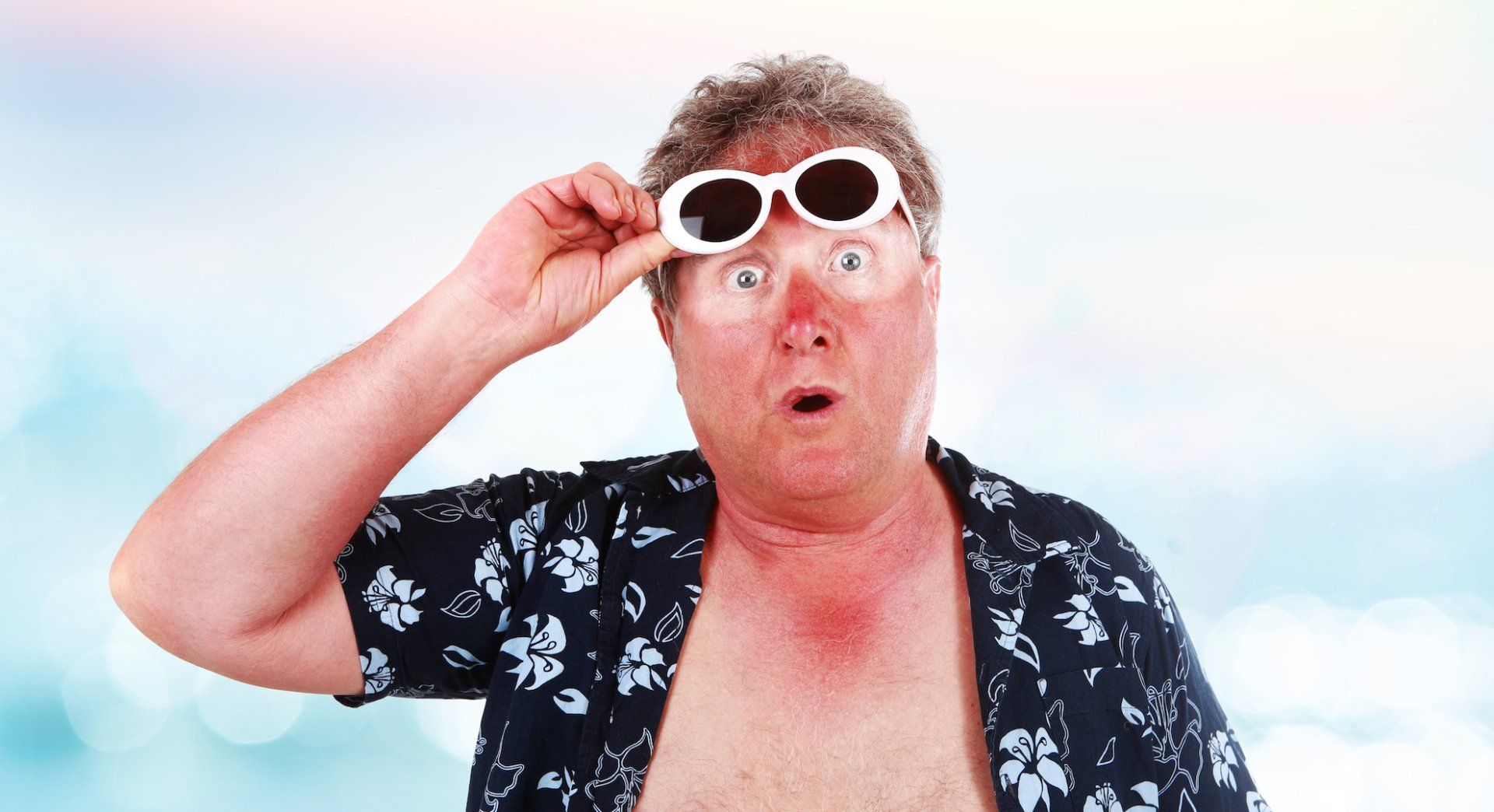 A shirtless man wearing sunglasses is making a surprised face