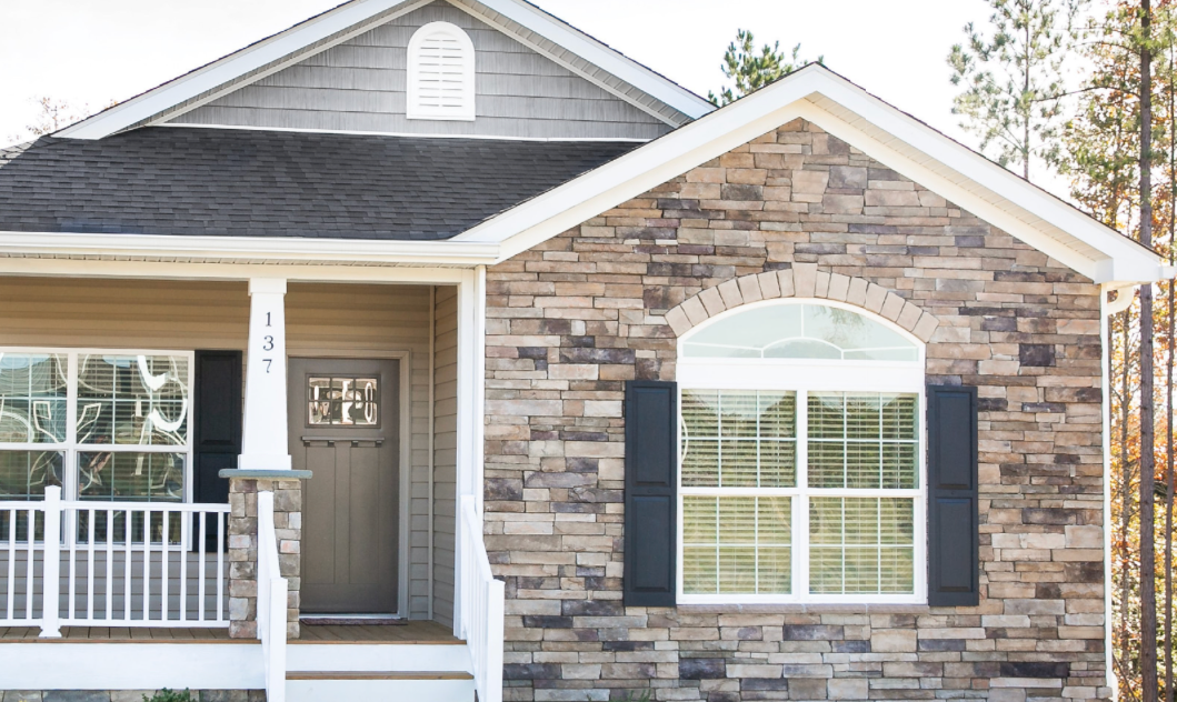 Front view of a brick bungalow with a front side porch with a white picket railing.
