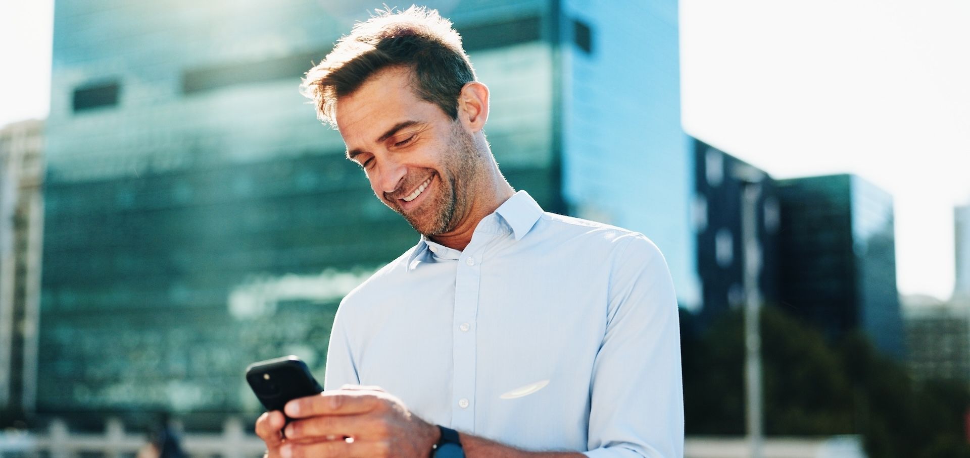 Smiling man looking at his rewards program results on his smartphone