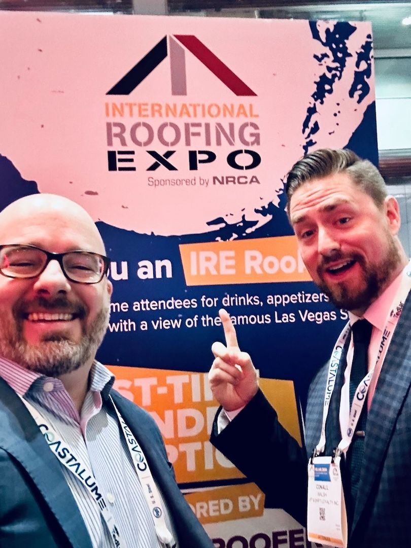 Two men are posing for a picture at the international roofing expo