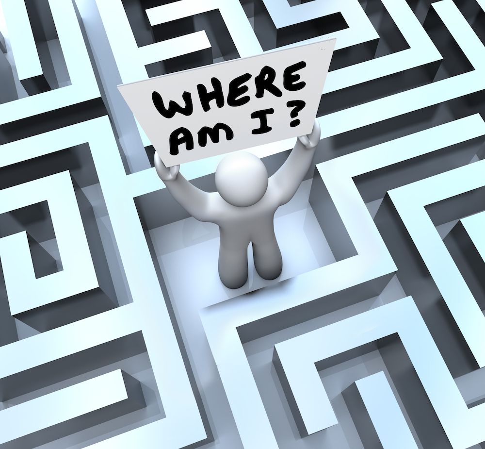 A man in a maze holding a sign that says where am i