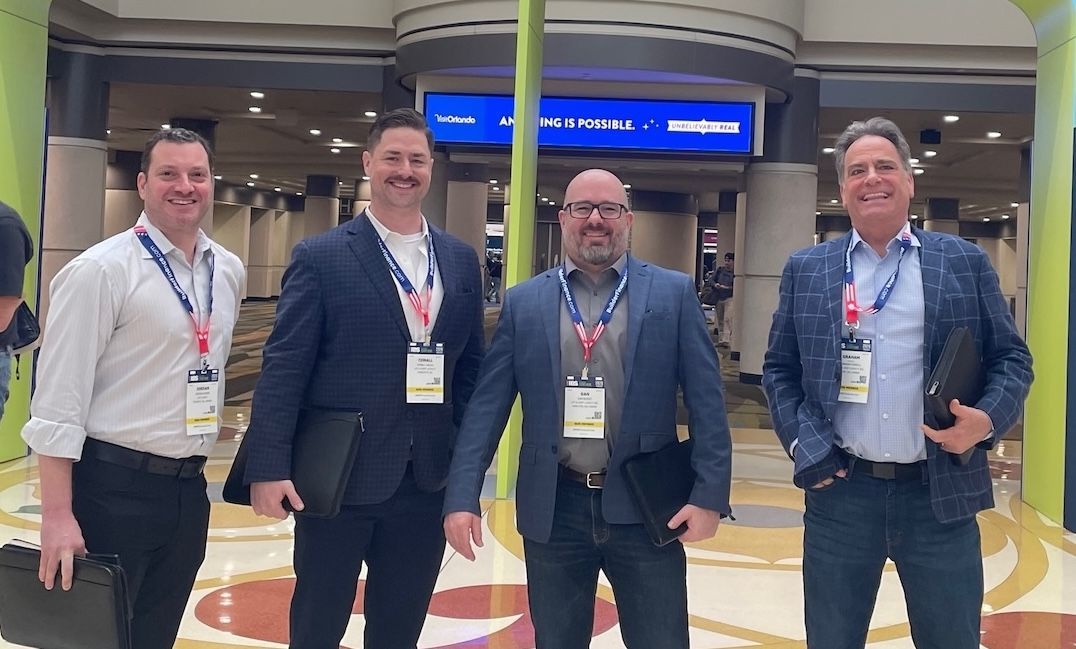 A group of people are standing in front of a large blue sign.