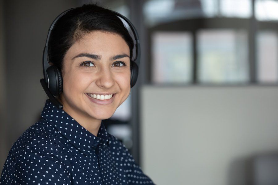 A woman wearing headphones is smiling and looking at the camera.