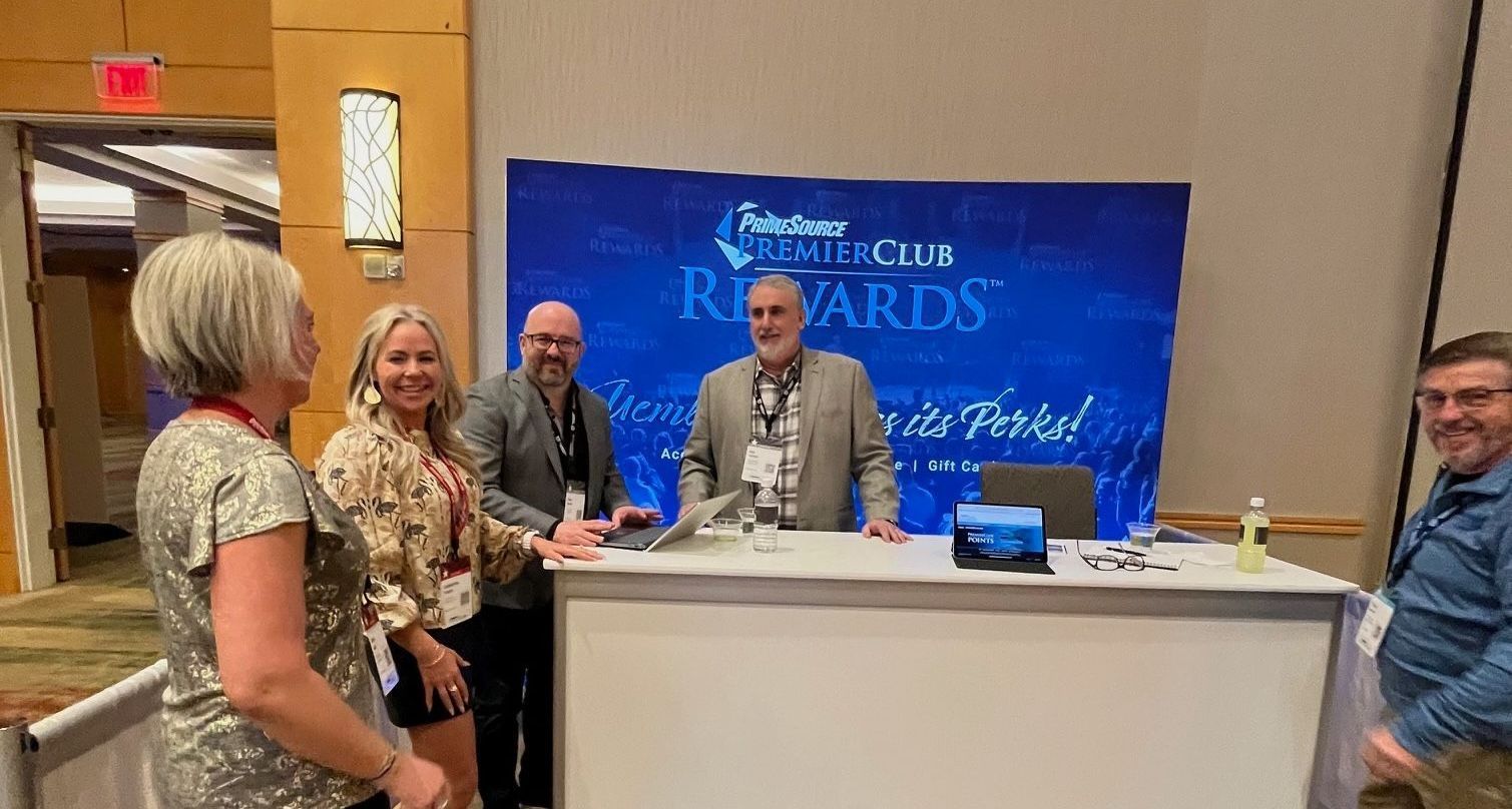 Two men standing in front of International Roofing Expo sign smiling