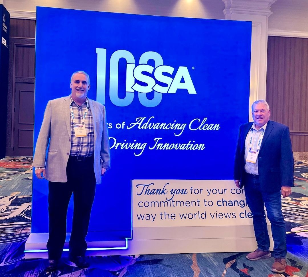 two men standing in front of a sign that says issa