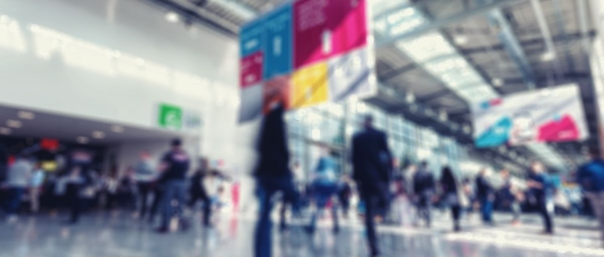 Blurred image of attendees walking through a trade show