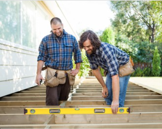 Two men are measuring a wooden deck with a level.