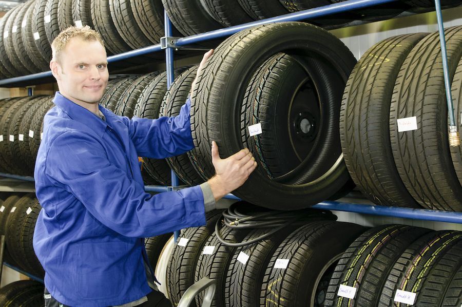 A man is holding a tire in a tire store.