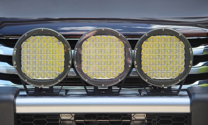 A close up of a car 's grille with three lights on it.