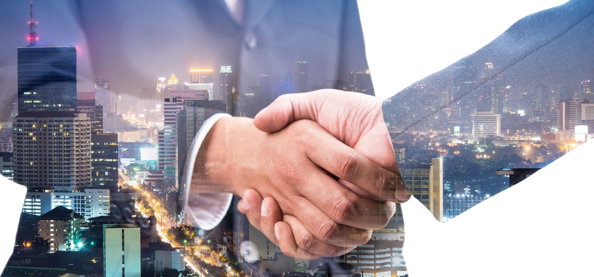 Two businessmen are shaking hands in front of a city skyline.