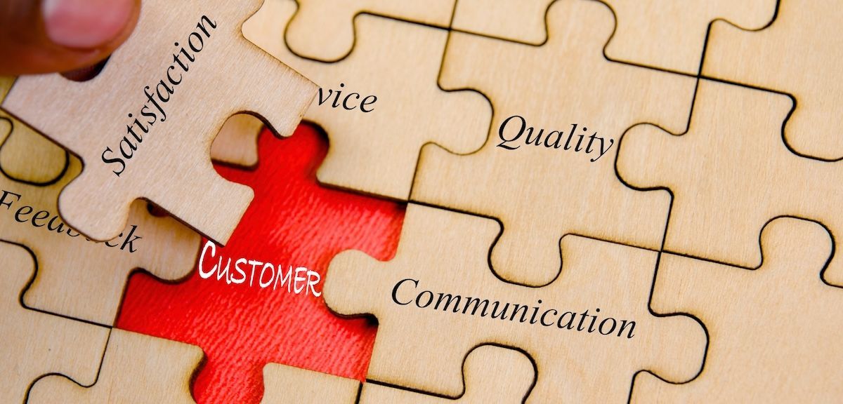 A person is holding a piece of a puzzle with the word customer on it