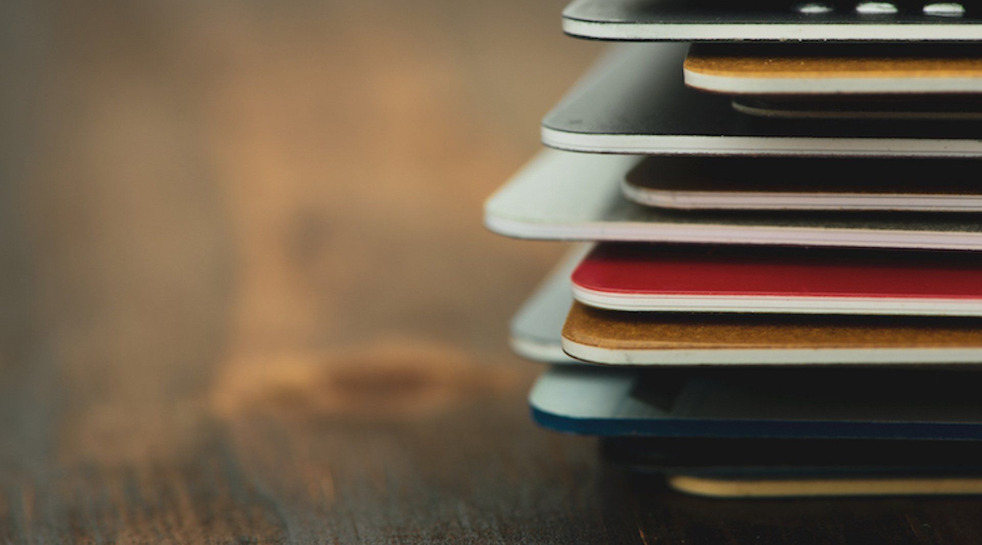 A stack of credit cards on a wooden table.