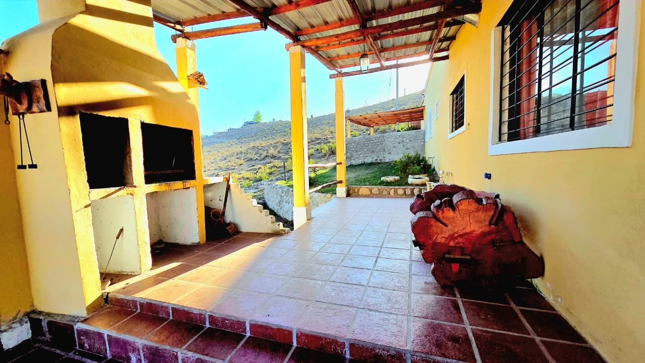 Patio cubierto con parrilla al aire libre, con vista a una ladera soleada.