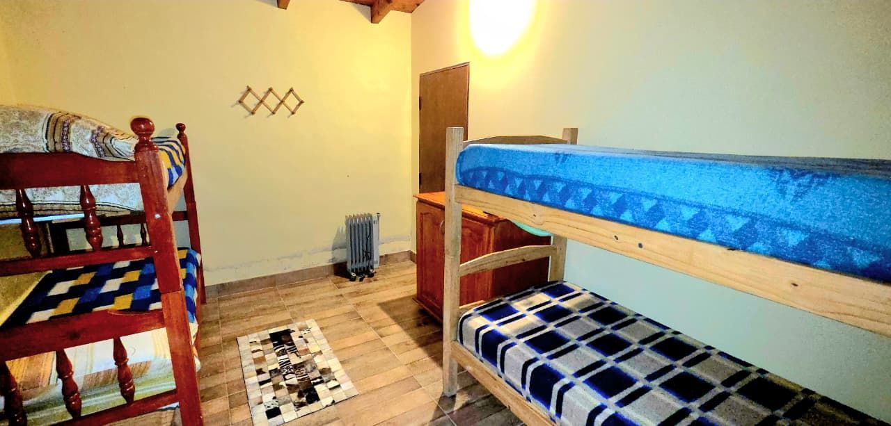 Una habitación con dos literas, una pequeña alfombra, un radiador y un perchero de pared.