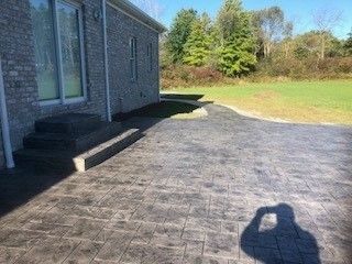 A gray house with a concrete driveway and a lush green lawn.