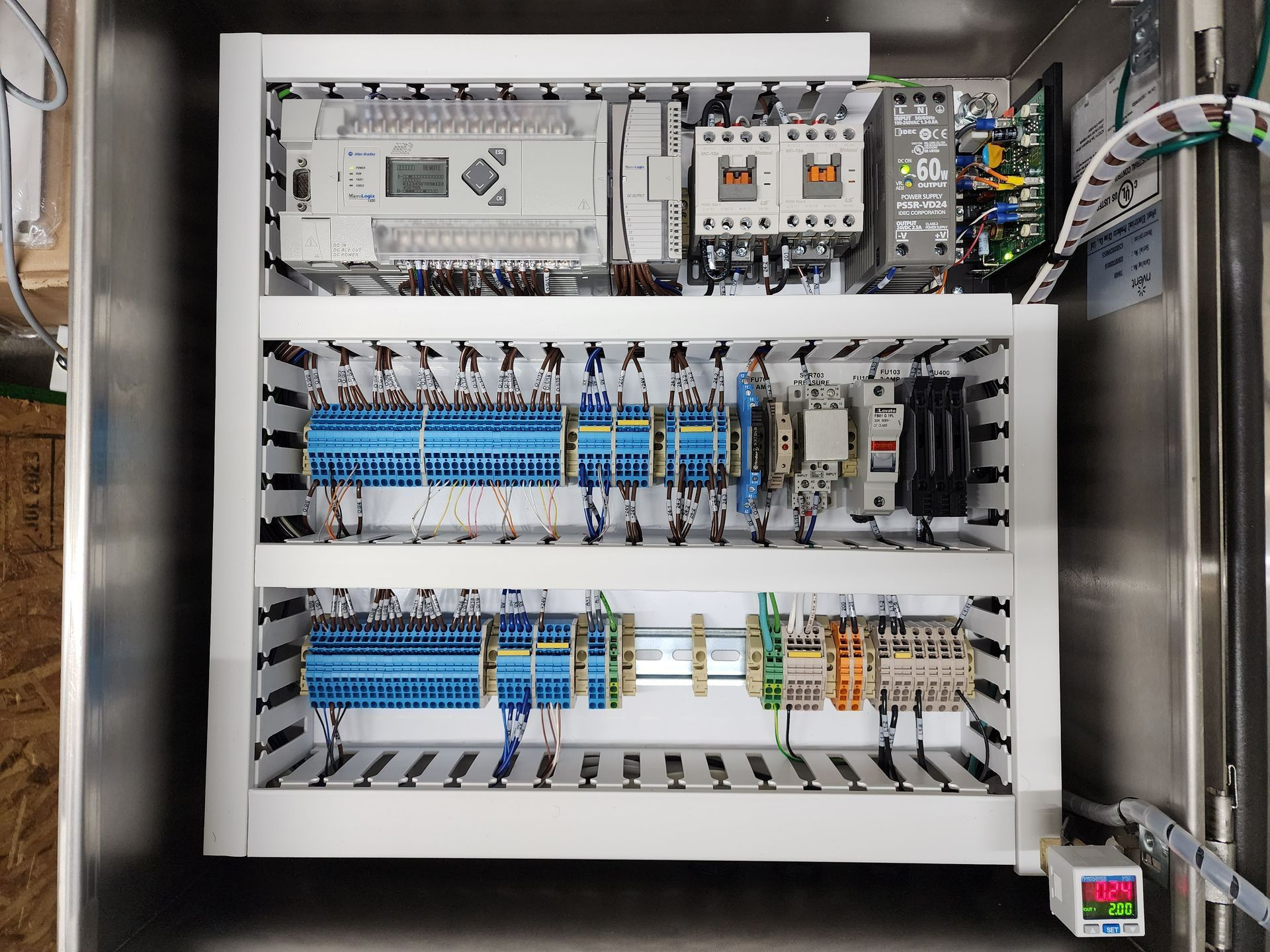 The inside of a stainless steel electrical box with lots of wires and connectors.