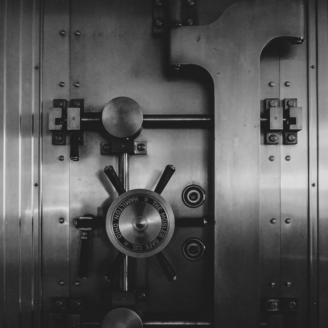 Bank vault door, metallic, closed, with large round dial and handle.