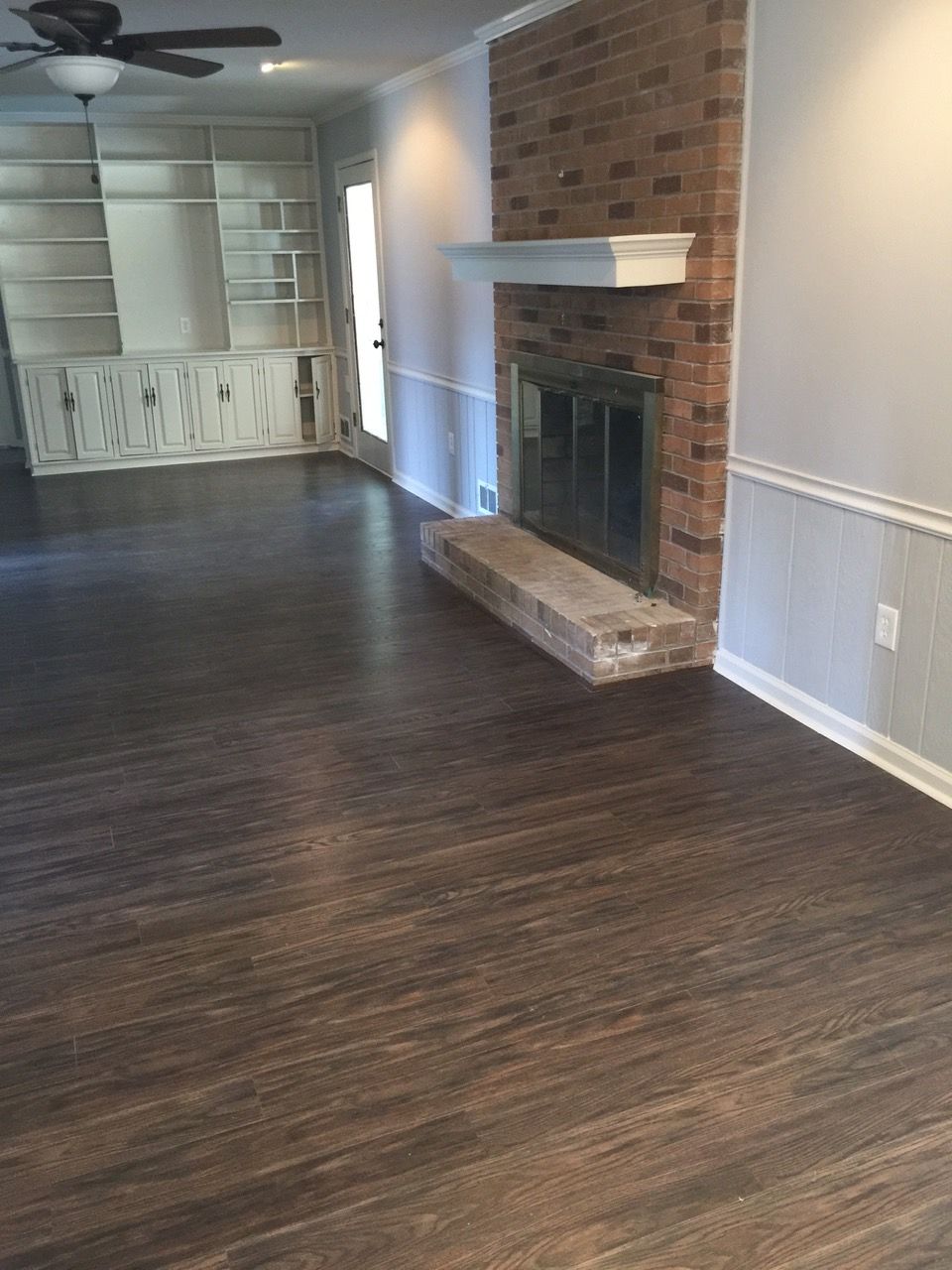 An empty living room with a fireplace and a ceiling fan.