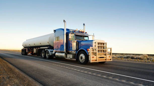 Blue hauler truck with a tank moving in an open road.