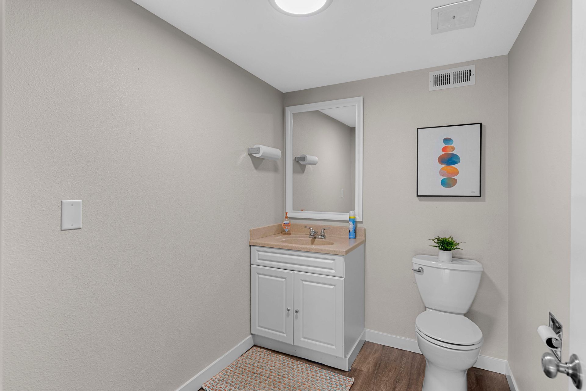 A bathroom with a toilet , sink and mirror.