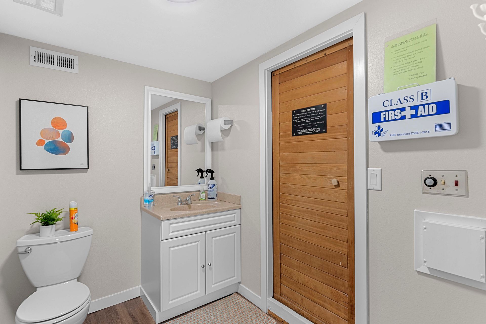 A bathroom with a toilet , sink and mirror.