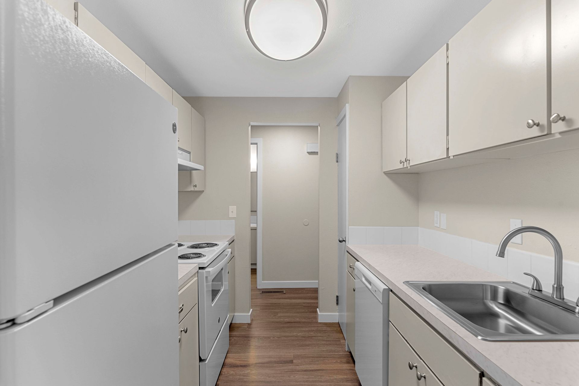A kitchen with a sink , refrigerator , stove and dishwasher.